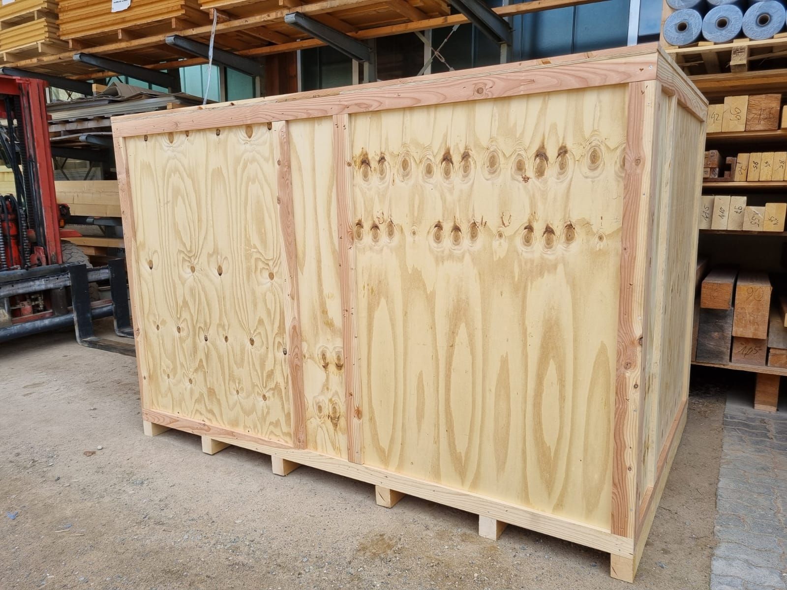 In einer Lagerhalle steht eine große Holzkiste auf dem Boden.