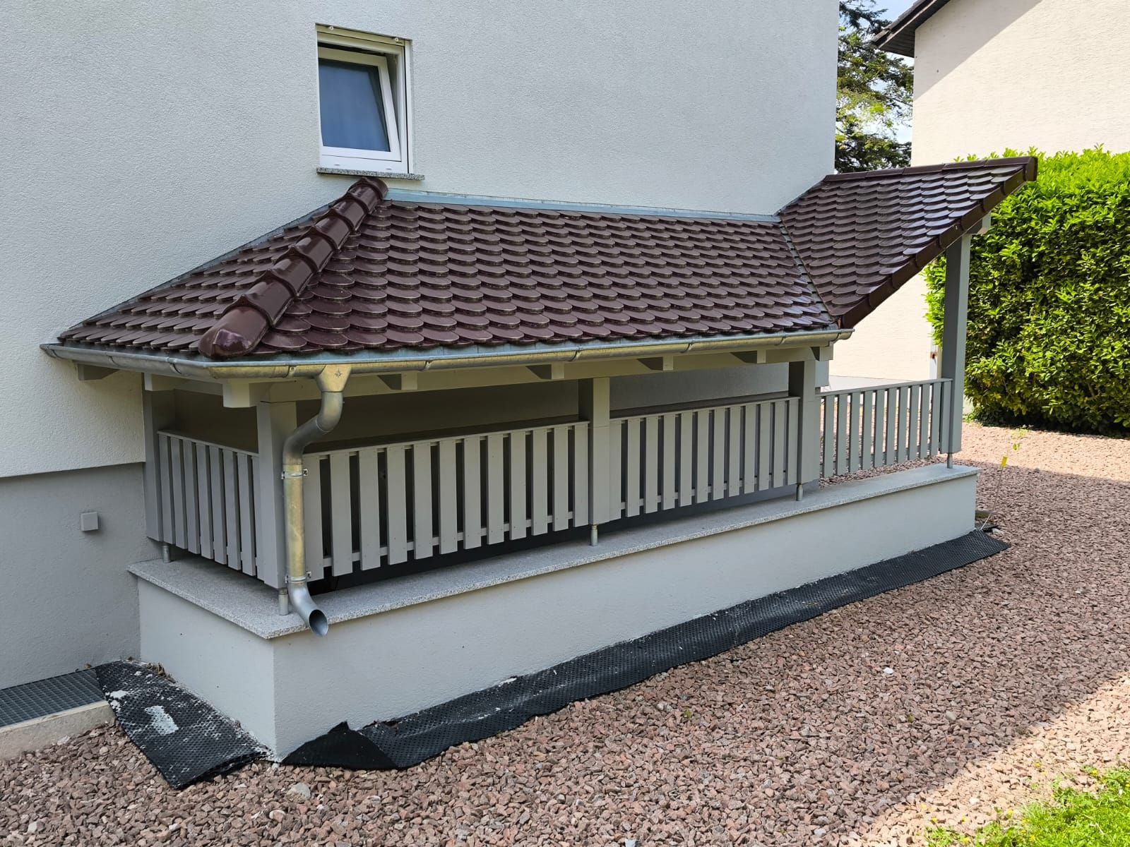 Ein weißes Haus mit einem braunen Dach und einer Veranda
