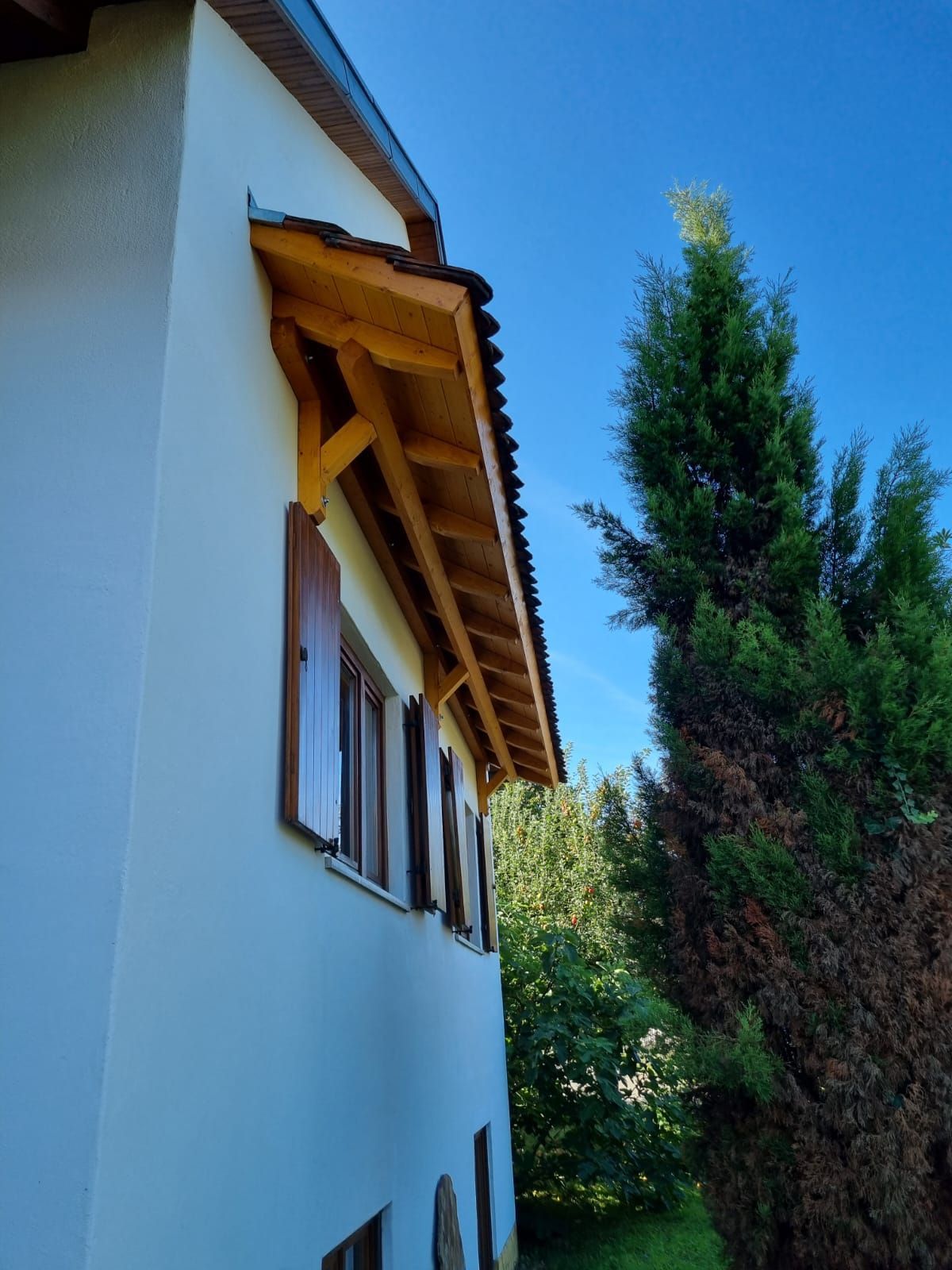 Ein weißes Haus mit Holzdach und Fensterläden