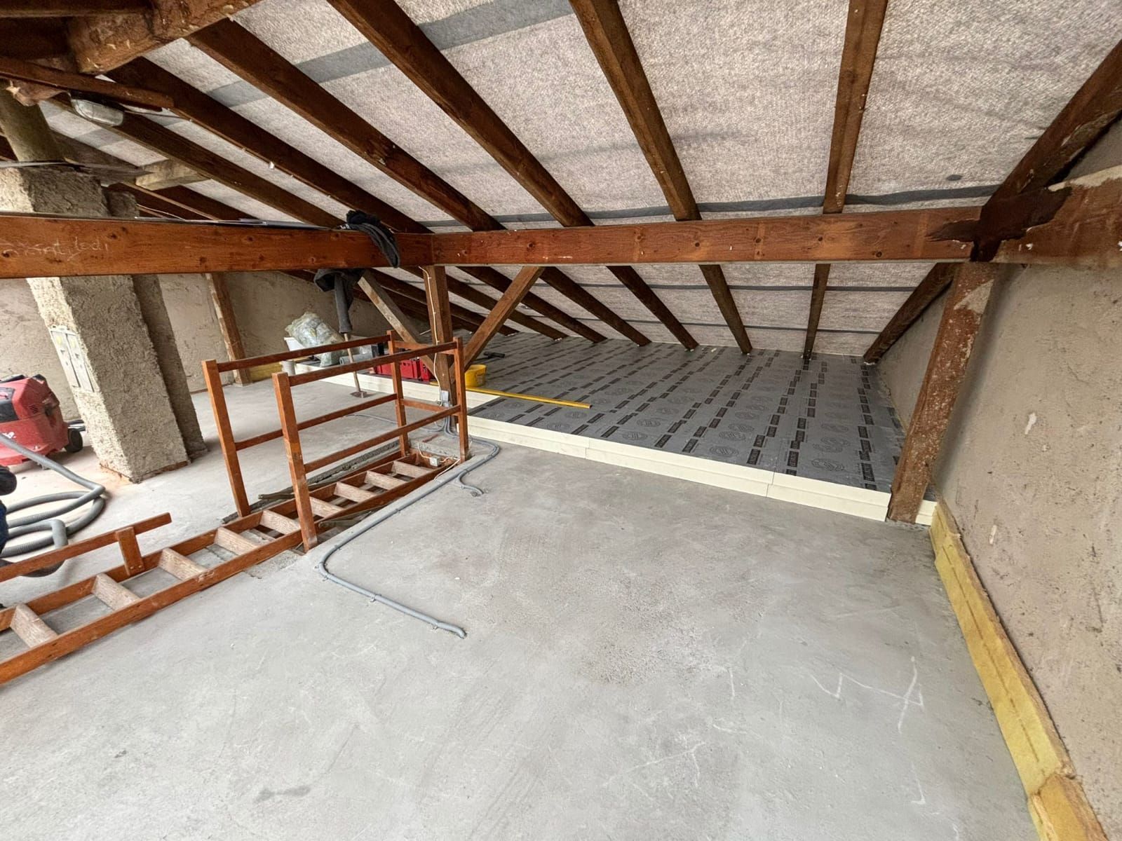 Ein Raum mit einer Leiter und einem Staubsauger darin.