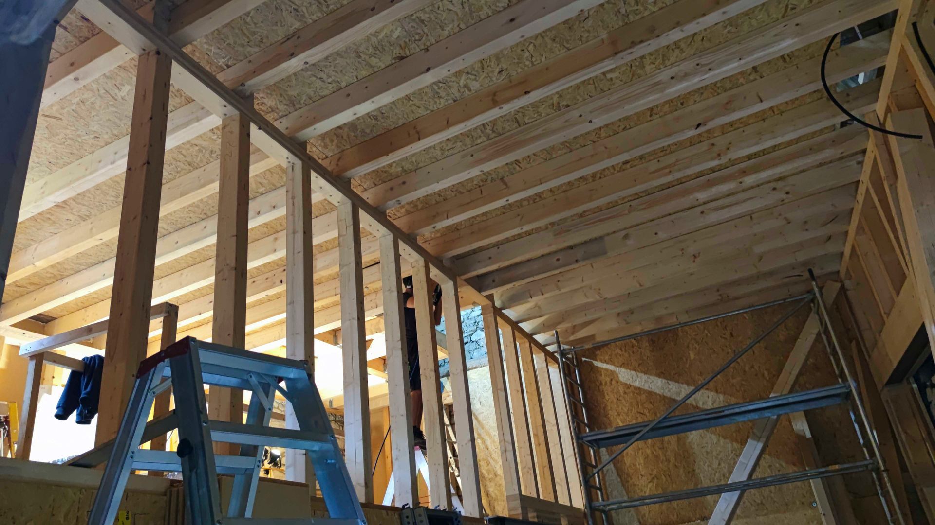 In der Mitte eines im Bau befindlichen Holzgebäudes steht eine Leiter.