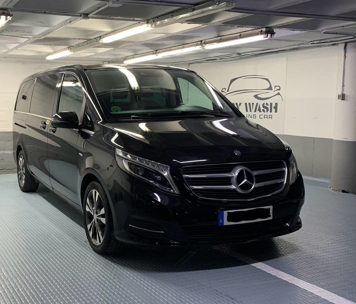 Furgoneta Mercedes negra estacionada dentro de un lavadero de coches.