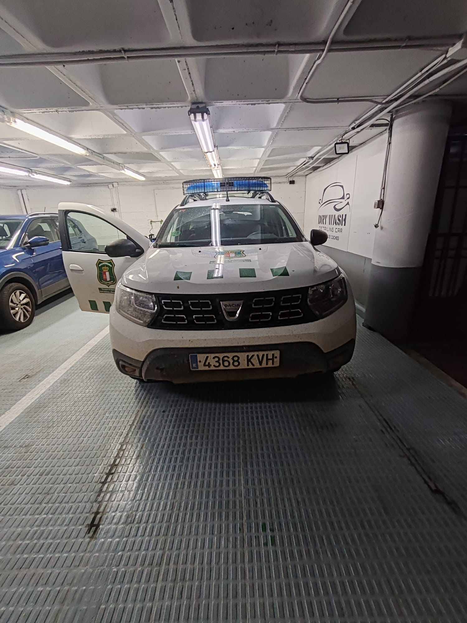 Vehículo policial Dacia Duster blanco y negro con luces azules intermitentes.
