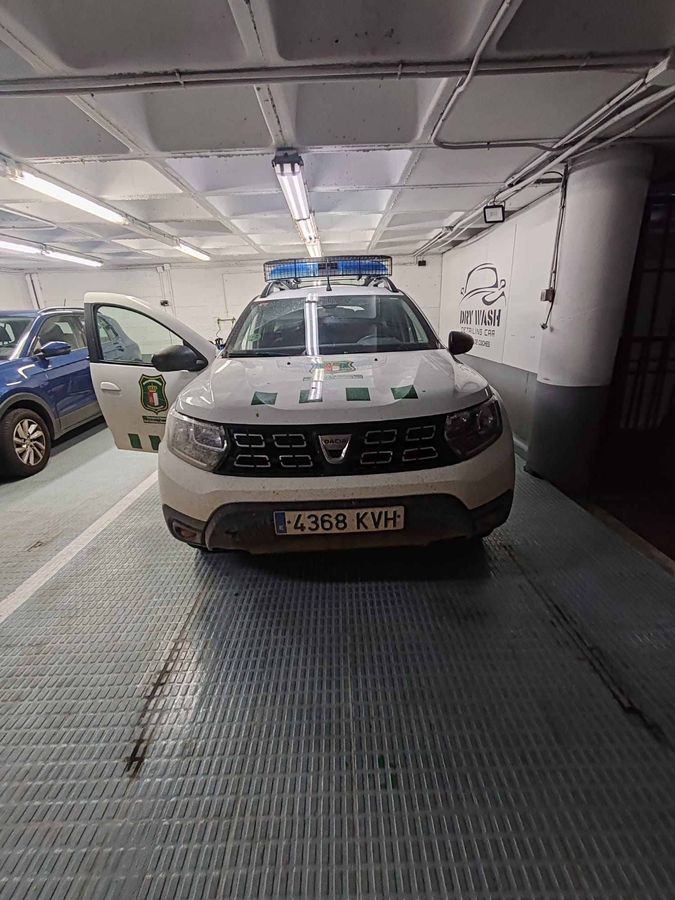 Vehículo policial Dacia Duster blanco y negro con luces azules intermitentes.