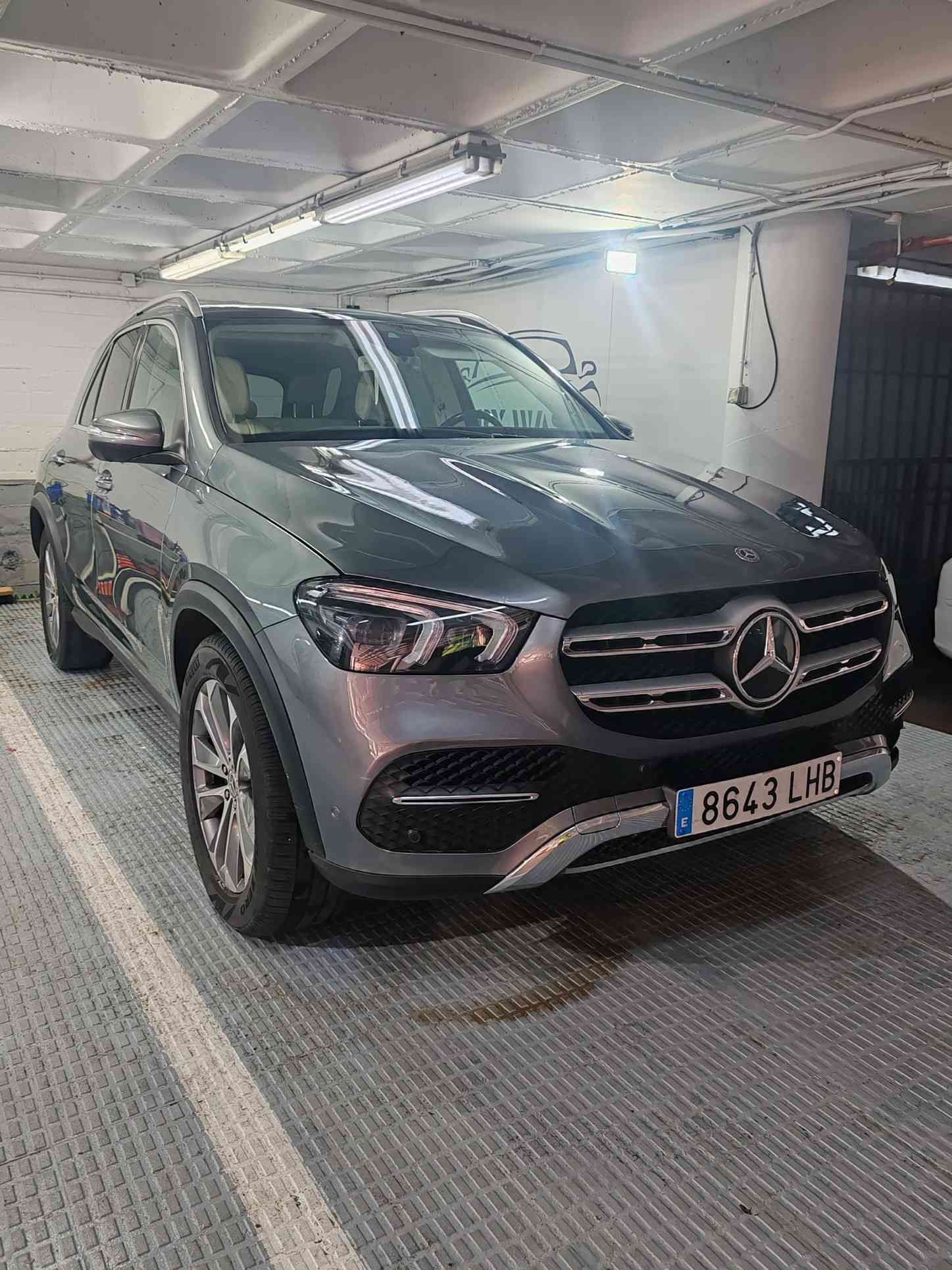 SUV Mercedes-Benz GLE gris aparcado en un garaje. Presenta parrilla plateada y detalles en los faros.