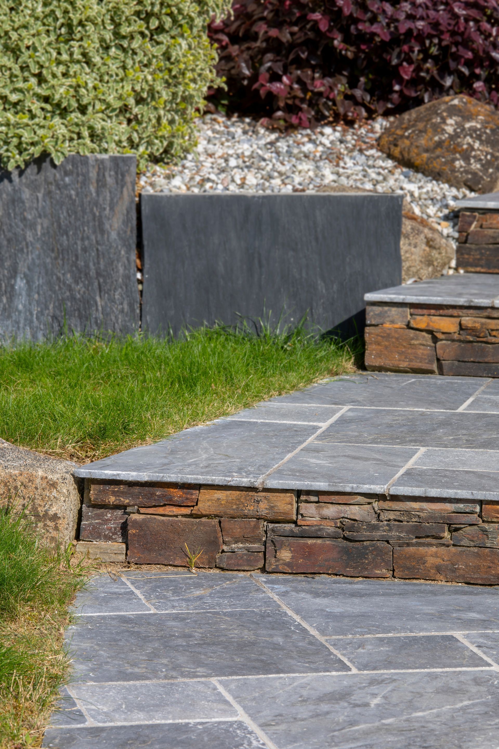 Des marches en pierre mènent à l'étage, bordées de pelouse et d'aménagements paysagers.