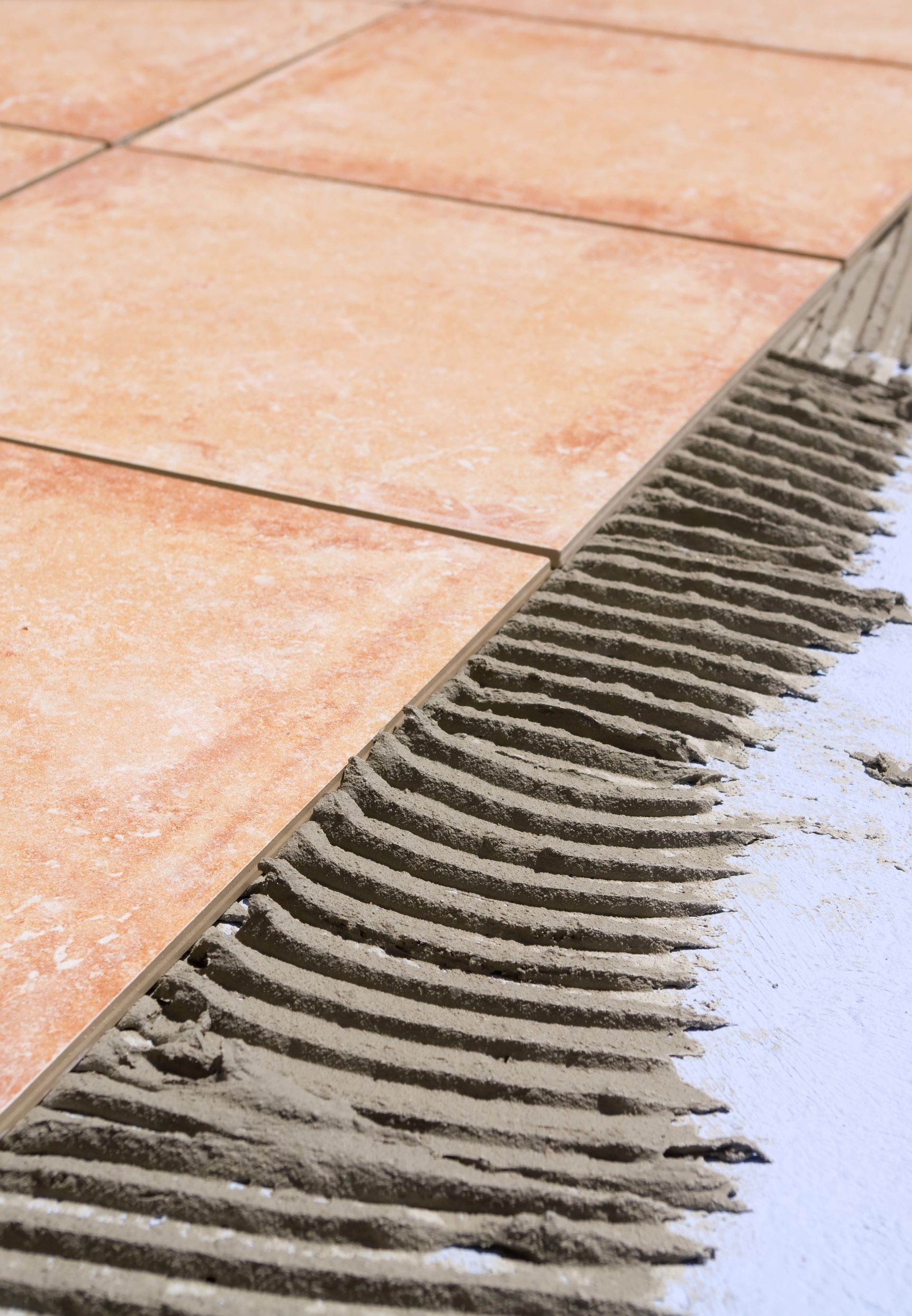 Pose de carreaux avec colle, montrant l'application crantée et l'espacement.