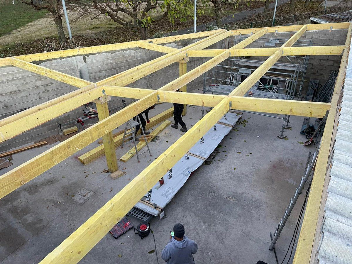 Des hommes travaillent sous une charpente