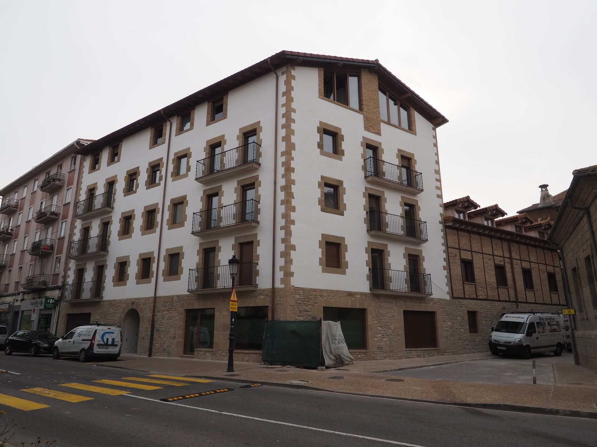 Edificio de varios pisos con fachada blanca y molduras marrones; vista a la calle.