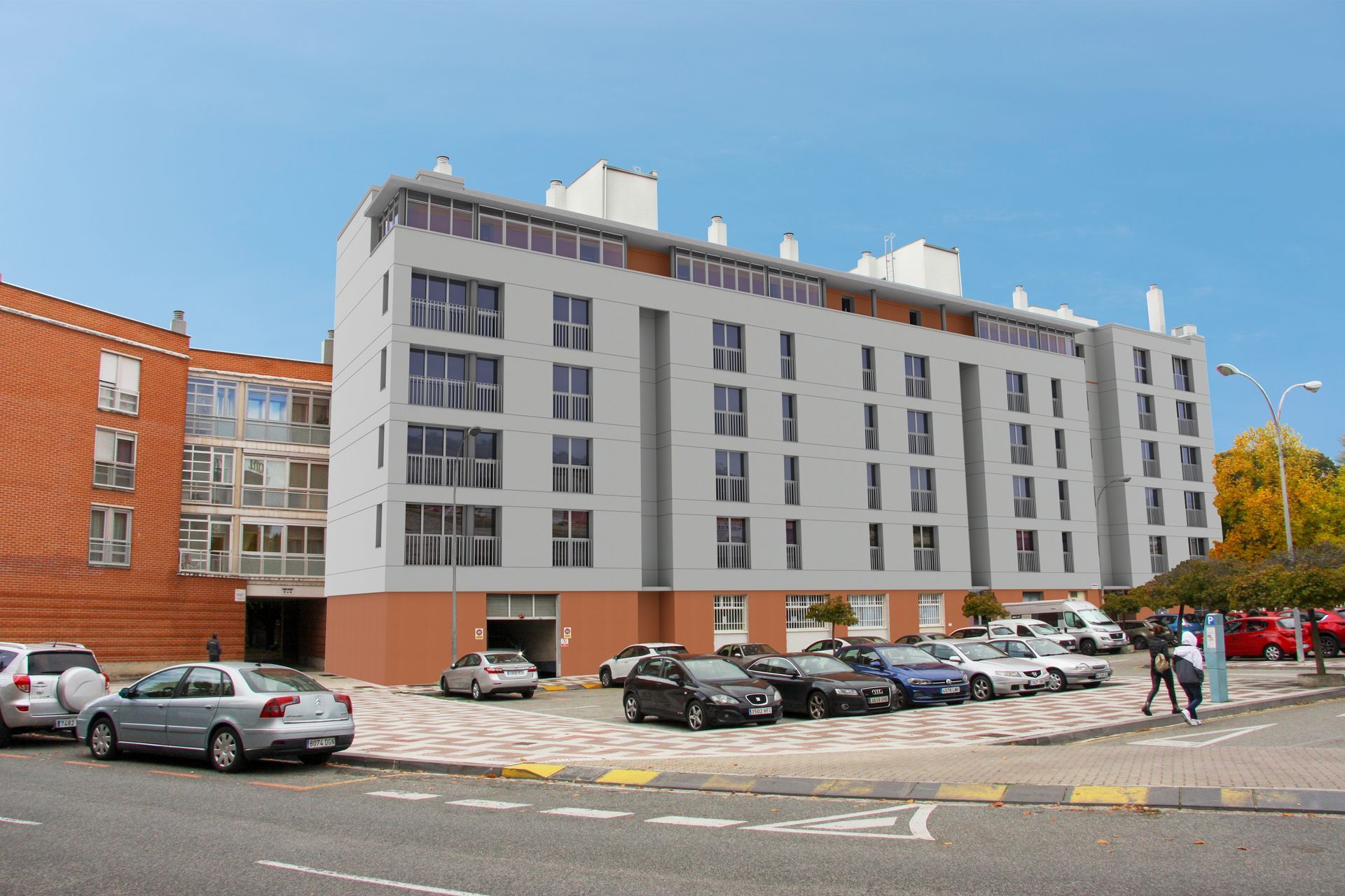 Edificio de apartamentos de varios pisos con autos estacionados al frente y peatones caminando por la acera.