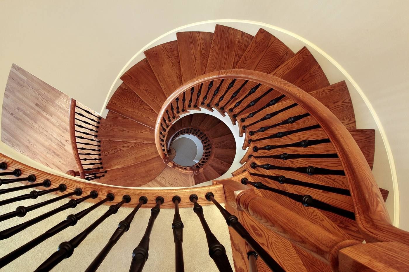 Escalera de madera en espiral vista desde abajo, con escalones de color marrón cálido que se retuercen hacia arriba.