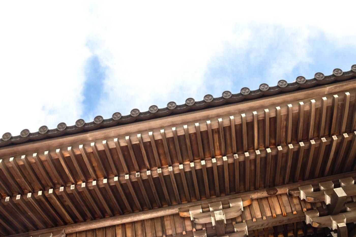 Primer plano del tejado de madera de un templo tradicional contra un cielo azul brillante.