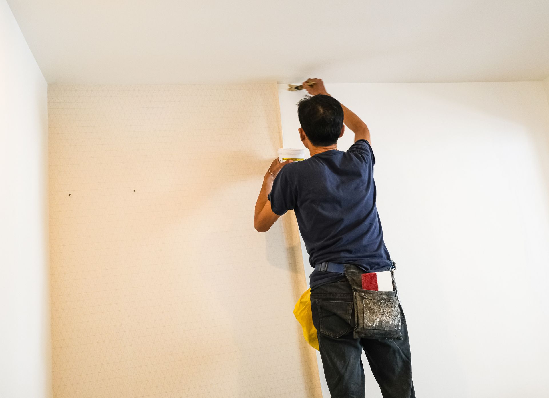 Un homme colle de la tapisserie sur un mur