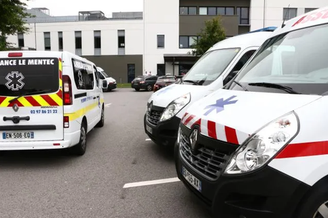 Ambulances garées à l'extérieur d'un bâtiment hospitalier moderne.