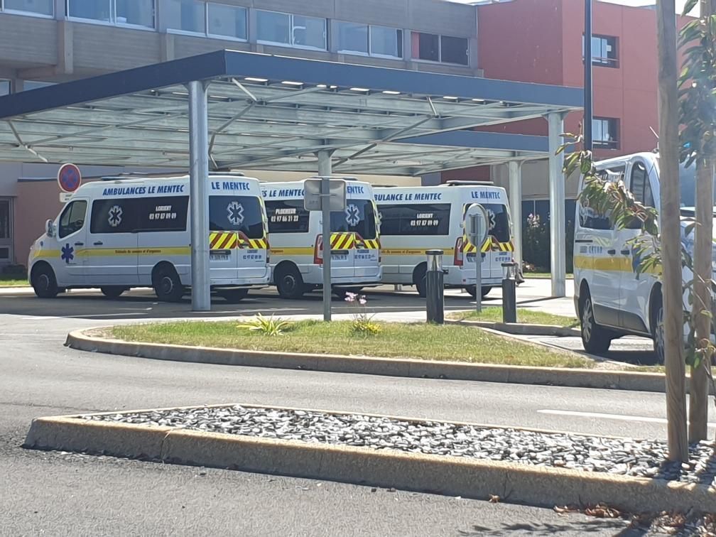 Ambulances garées sous un auvent à l'extérieur d'un bâtiment hospitalier.