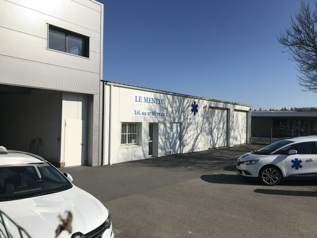 Bâtiment blanc avec deux ambulances garées à l'extérieur.