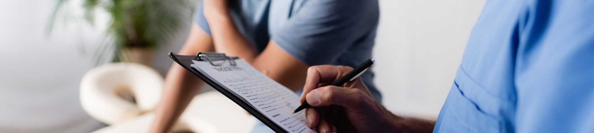 Une personne prend des notes sur un bloc-notes ; une autre personne se tient l'épaule.