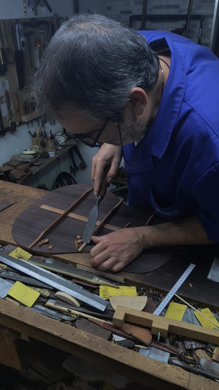 Un hombre con una camisa azul está trabajando en un trozo de madera.