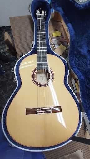 Una guitarra está dentro de un estuche azul sobre una mesa.