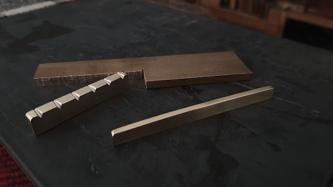 Tres piezas de metal están sobre una mesa.