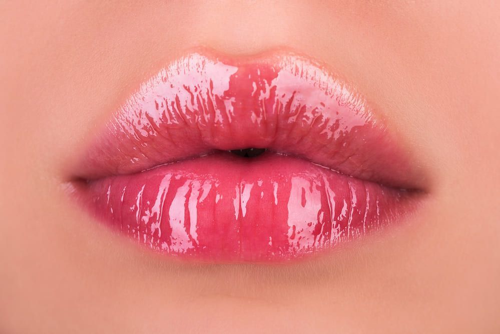 Un primer plano de los labios de una mujer con lápiz labial rosa.