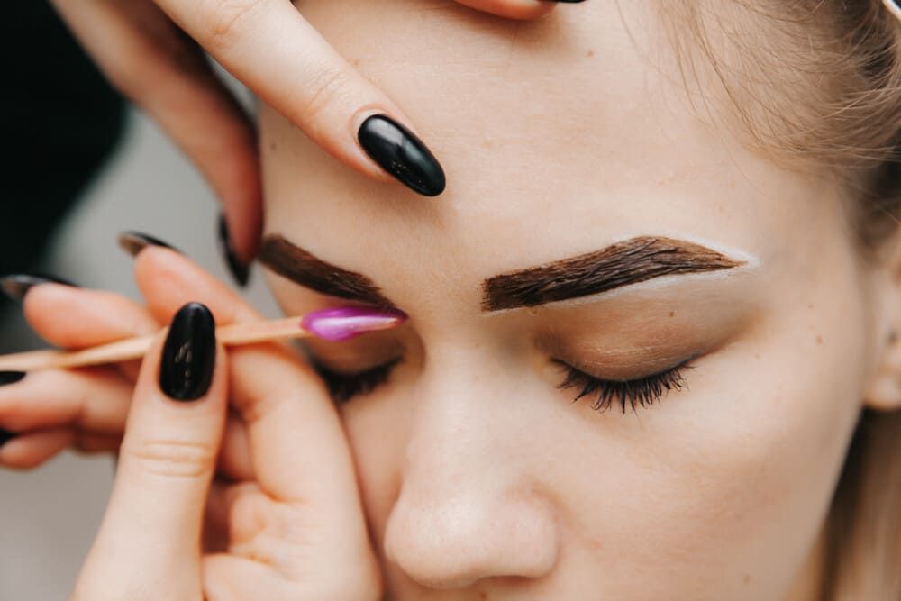 Una mujer se está pintando las cejas con un maquillador.