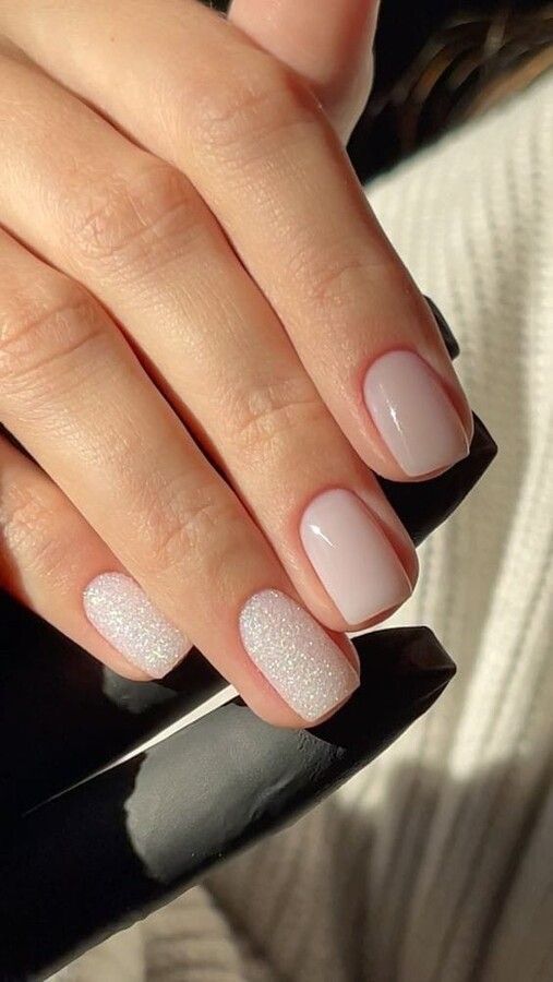 Un primer plano de las uñas de una mujer con esmalte de uñas blanco.