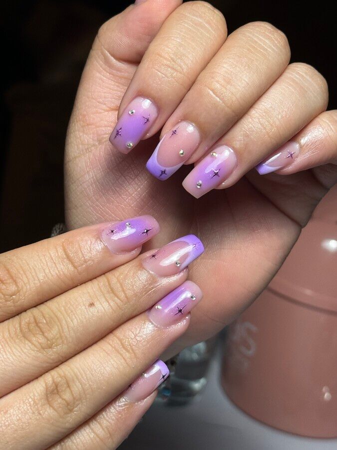 Un primer plano de la mano de una mujer con uñas moradas.