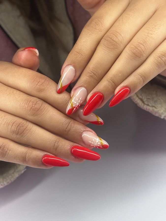 Un primer plano de las uñas de una mujer con diseños rojos y dorados.