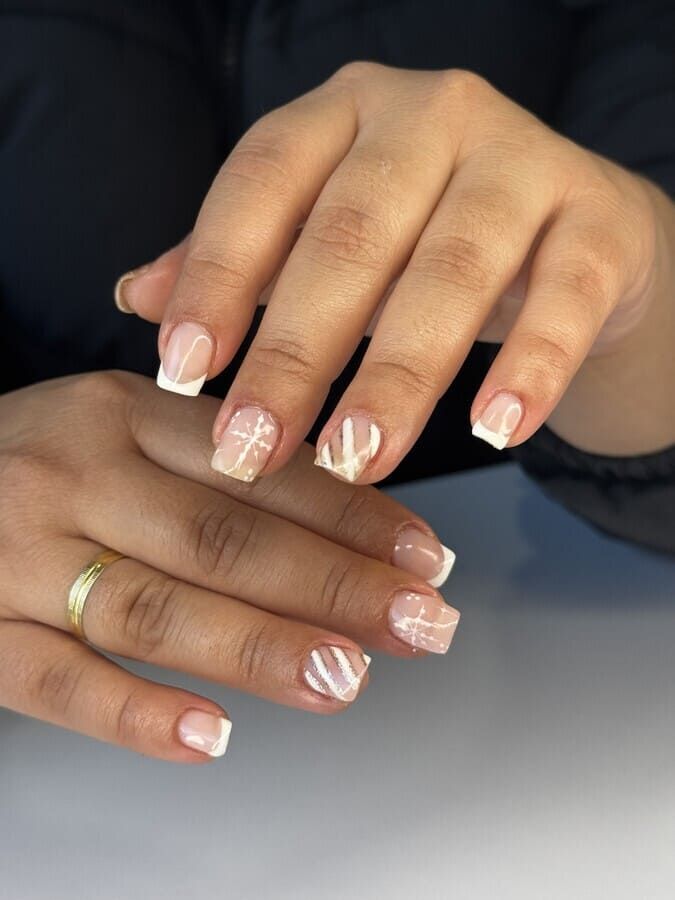 Un primer plano de las uñas de una mujer con manicura francesa.