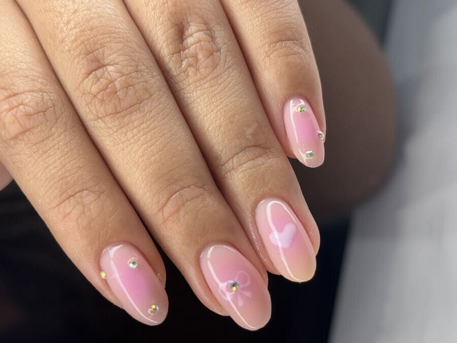 Un primer plano de las uñas de una mujer con un diseño de corazón rosa.