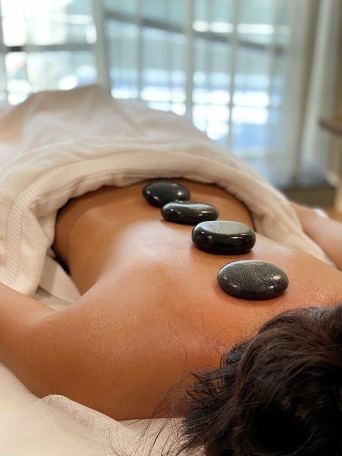 Una mujer está recibiendo un masaje con piedras calientes en la espalda.