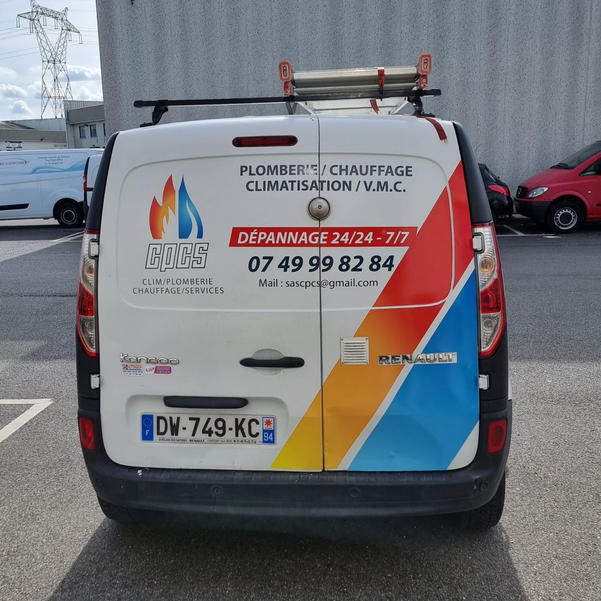 Vue arrière d'une camionnette Renault blanche avec le logo d'une entreprise de plomberie et de climatisation, ses coordonnées et sa plaque d'immatriculation.