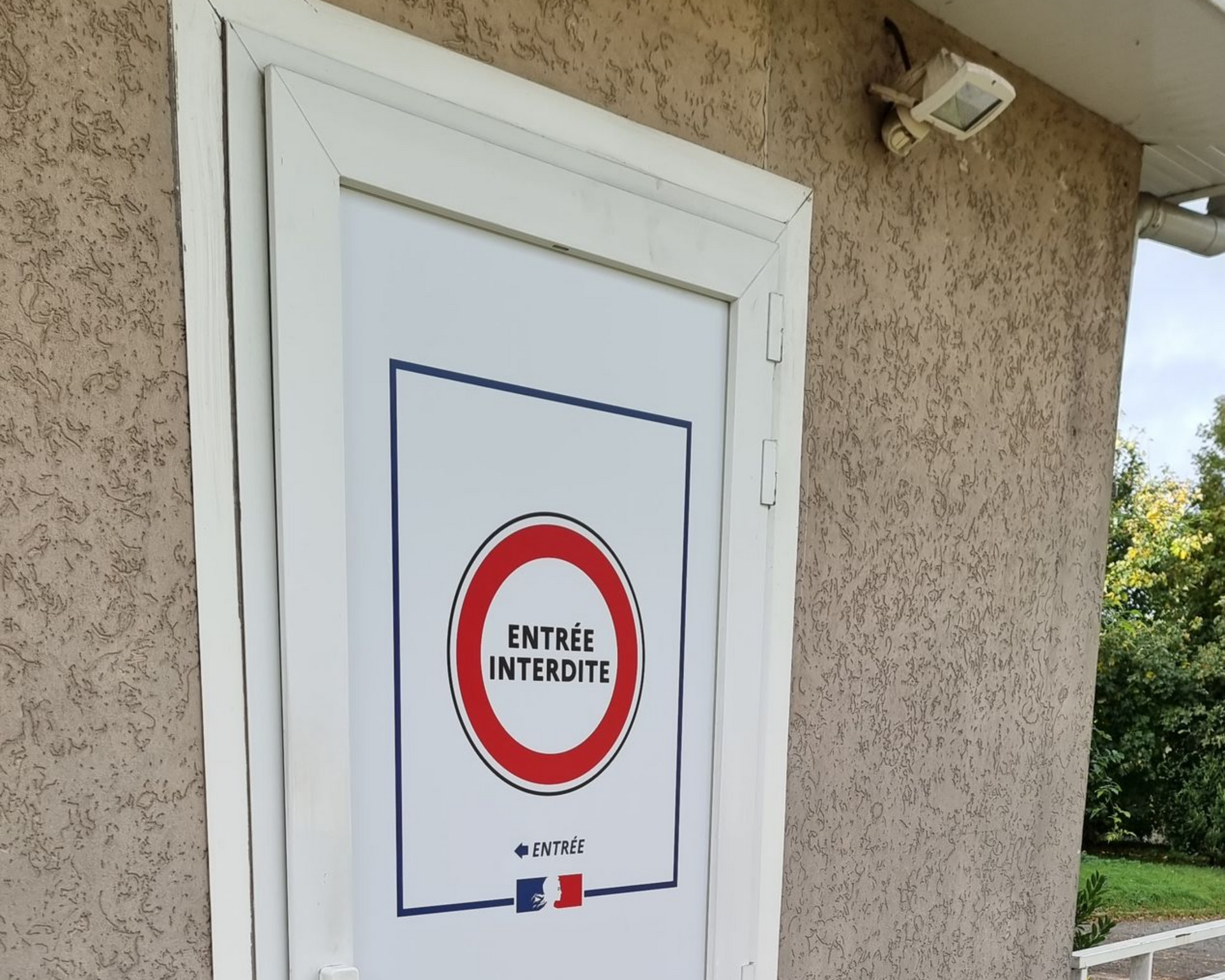 Porte blanche avec inscription entrée interdite dans un cercle rouge.