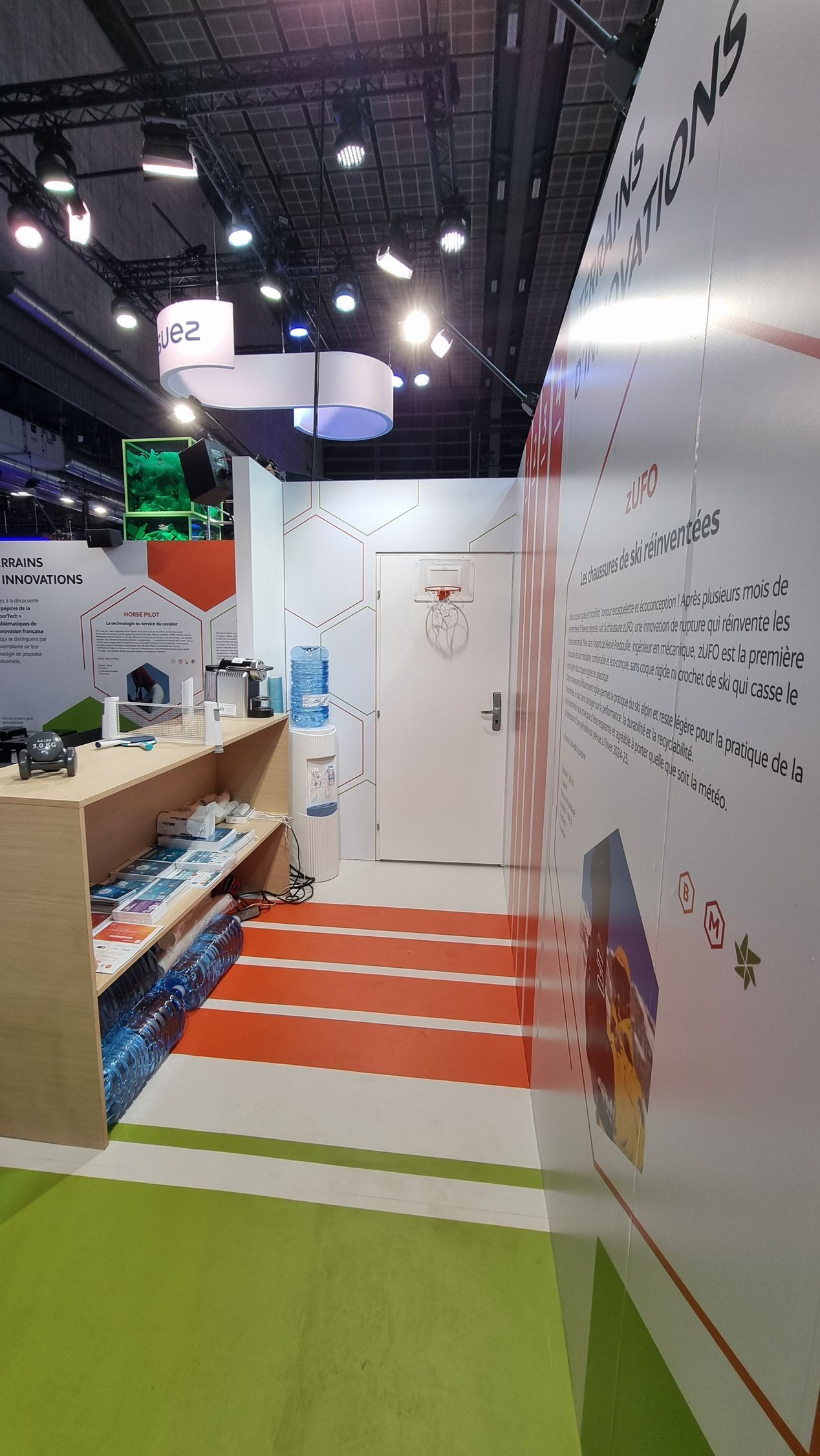 Entrée de hall d'exposition avec une porte blanche, un escalier et un comptoir présentant des produits