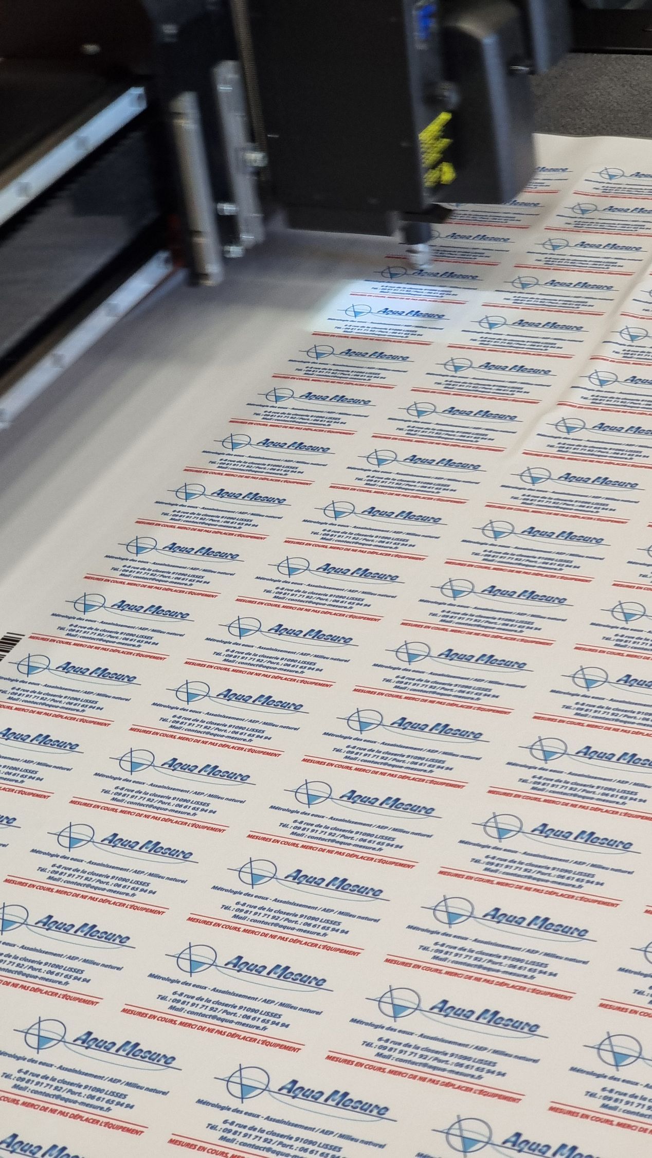 Découpe à la machine de cartes de visite imprimées sur une grande feuille de papier.