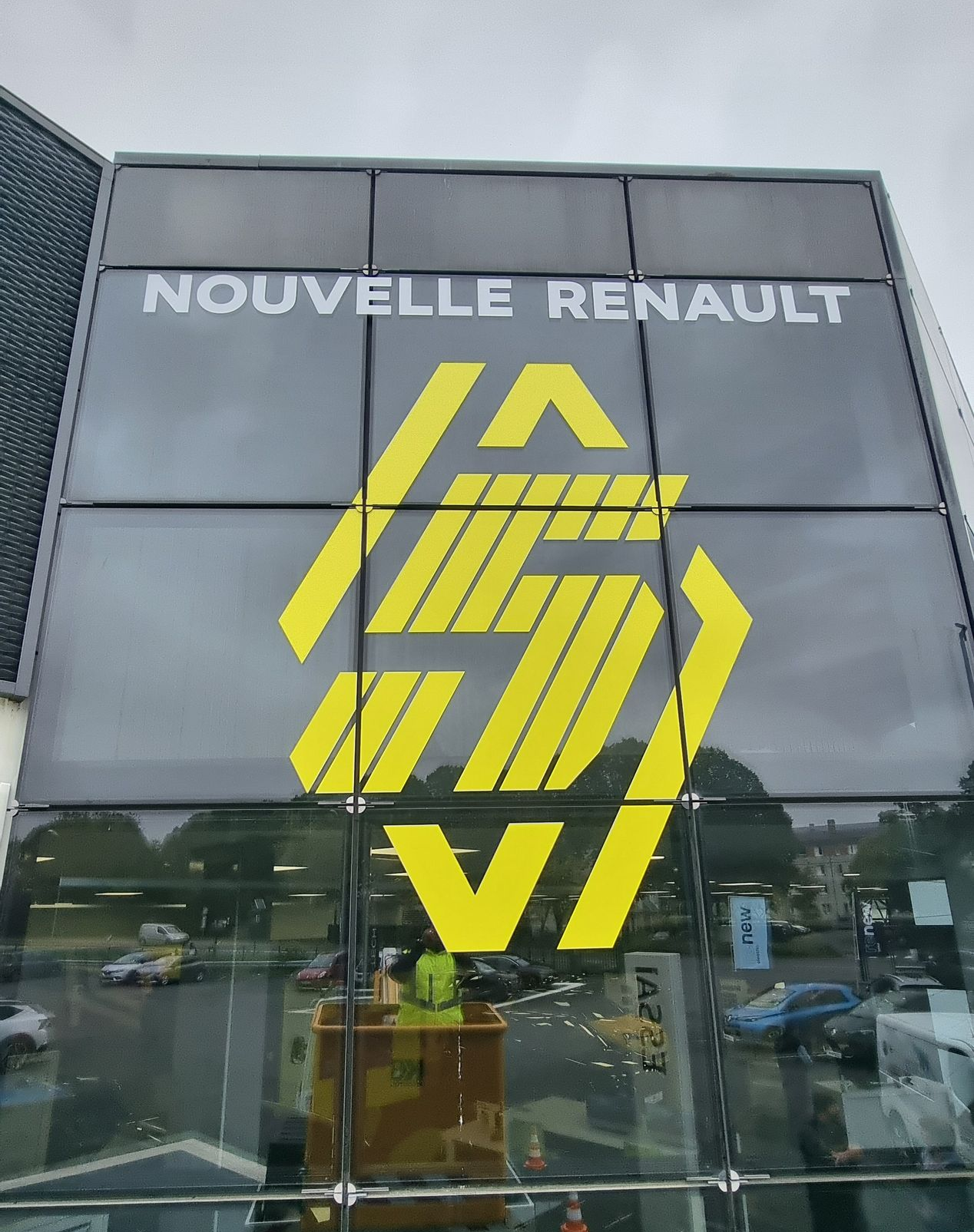 Panneau Nouvelle Renault avec logo jaune sur un bâtiment vitré