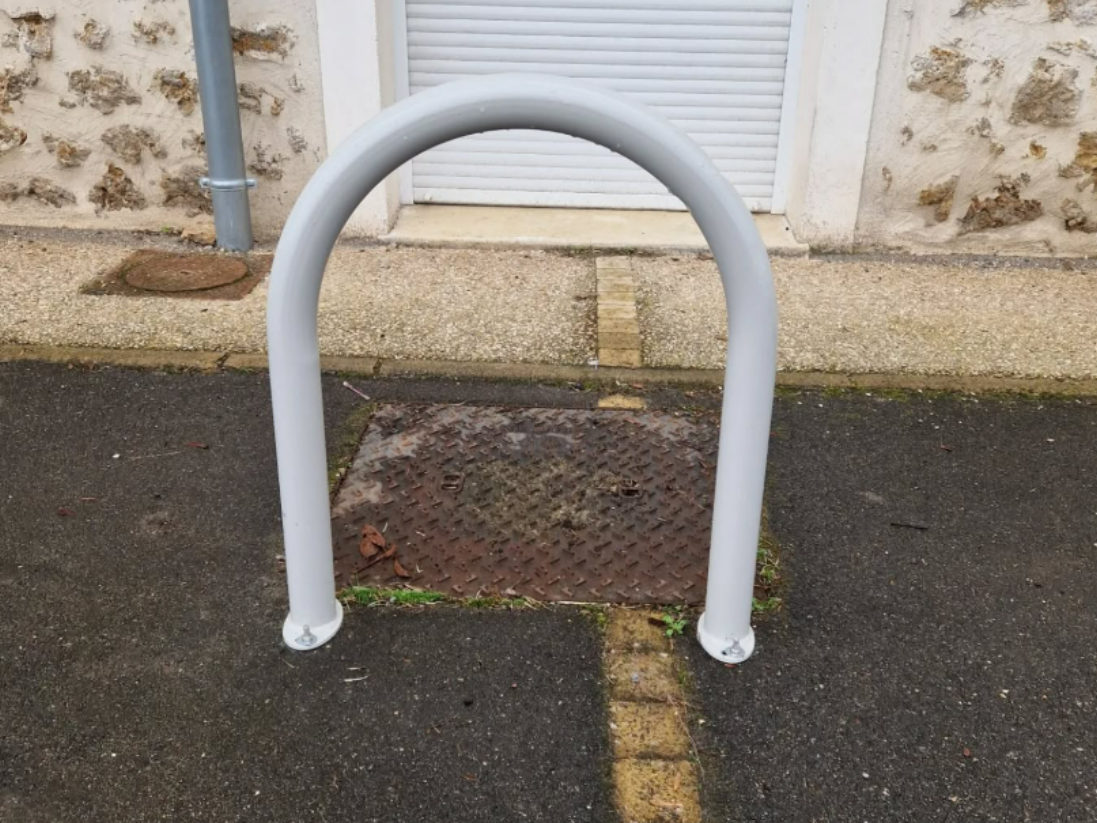 Arceau de sécurité devant un bâtiment à façade en pierre texturée