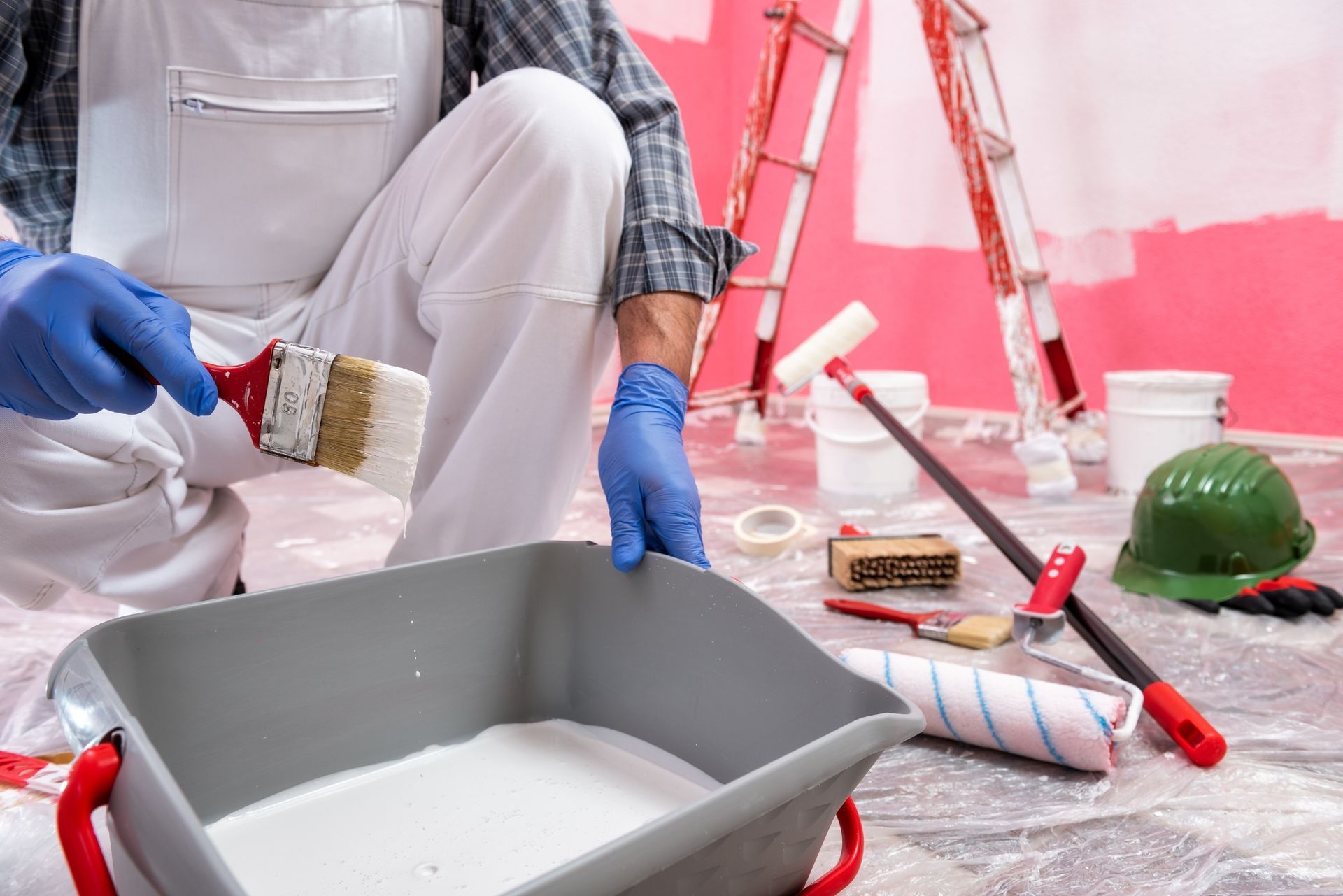 Un hombre está pintando una pared con un pincel y un cubo de pintura.