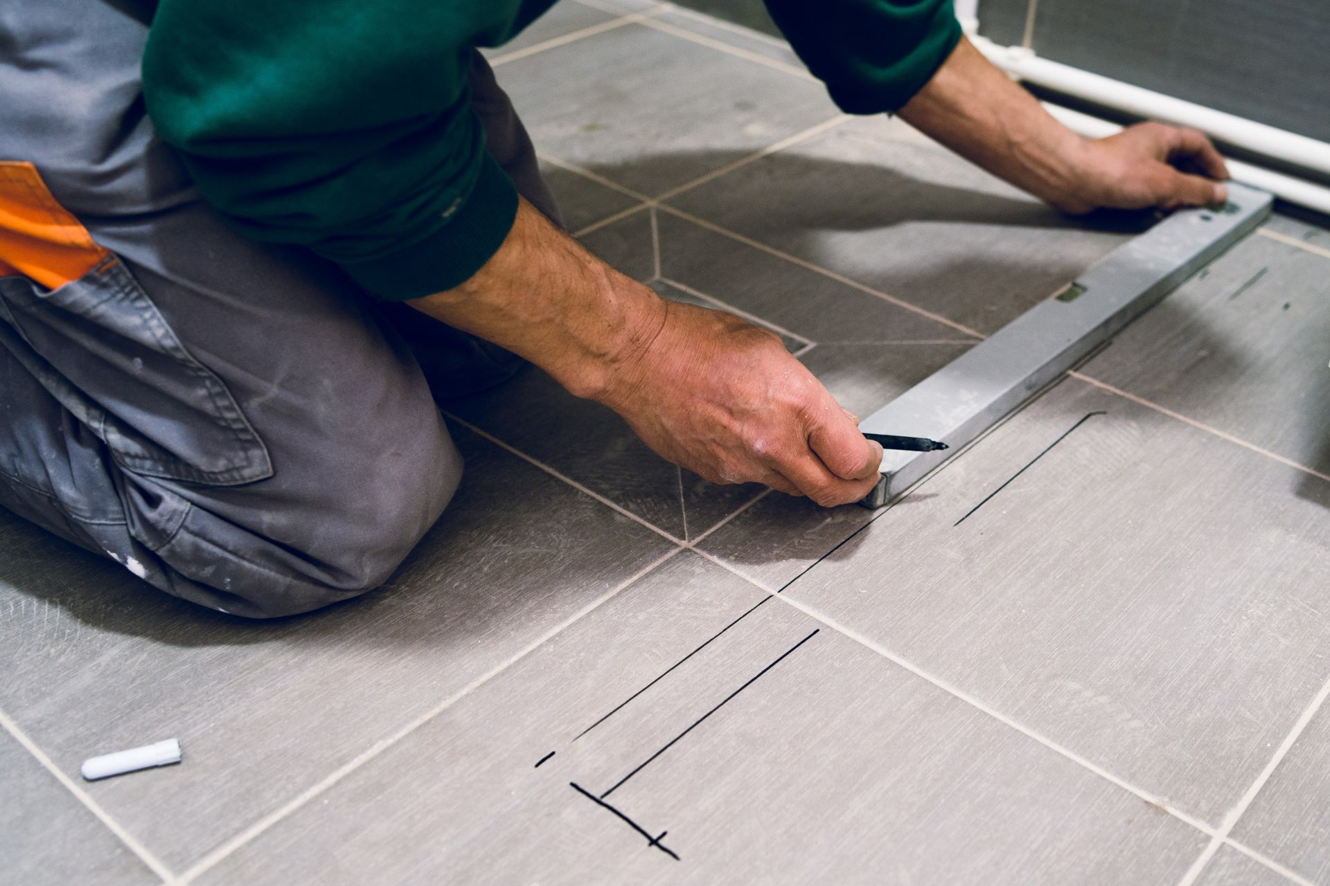 Un hombre está midiendo un piso de baldosas con una regla.