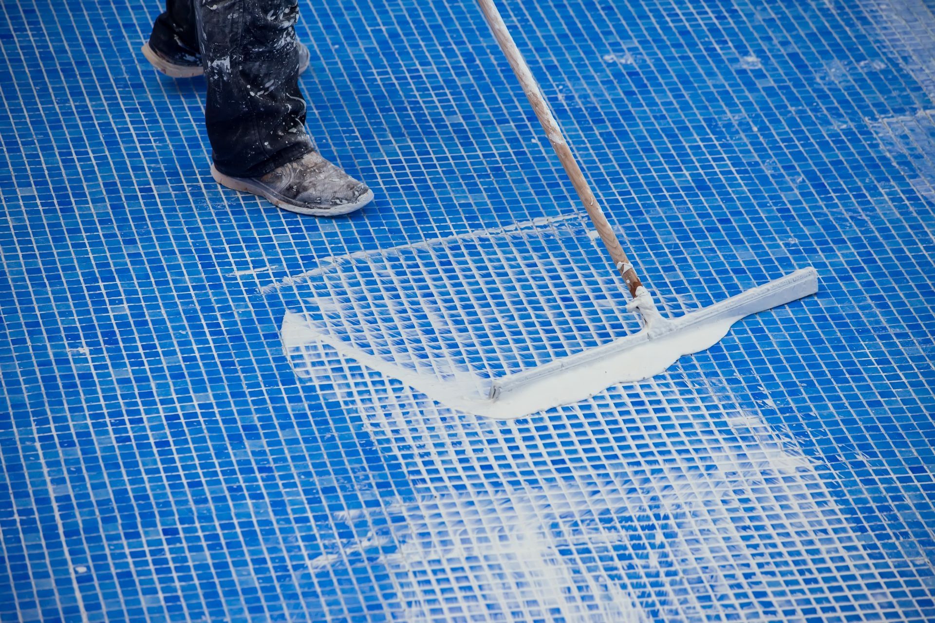 Una persona está limpiando una piscina con un rastrillo.