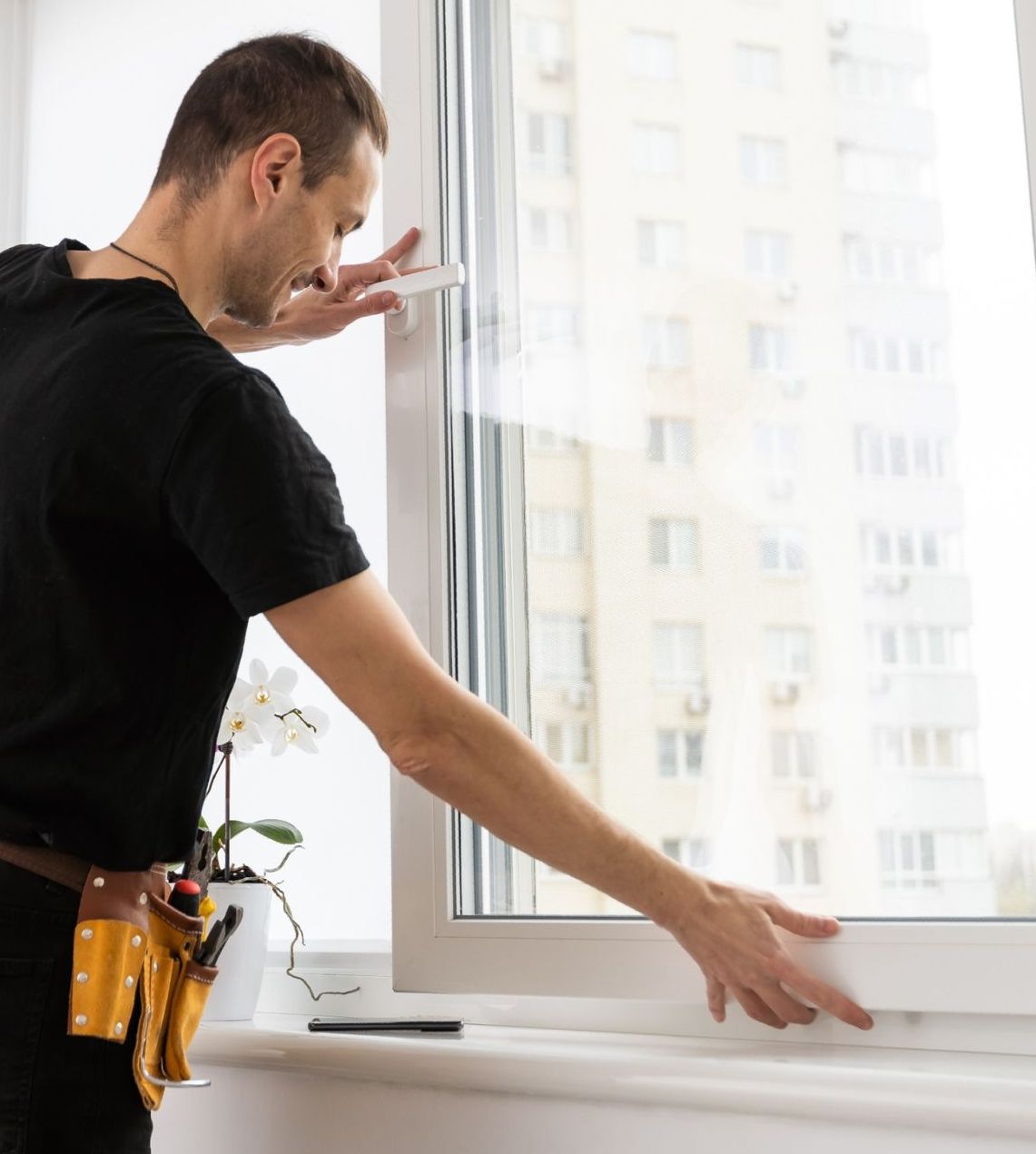 Un hombre está parado frente a una ventana mirando hacia afuera.