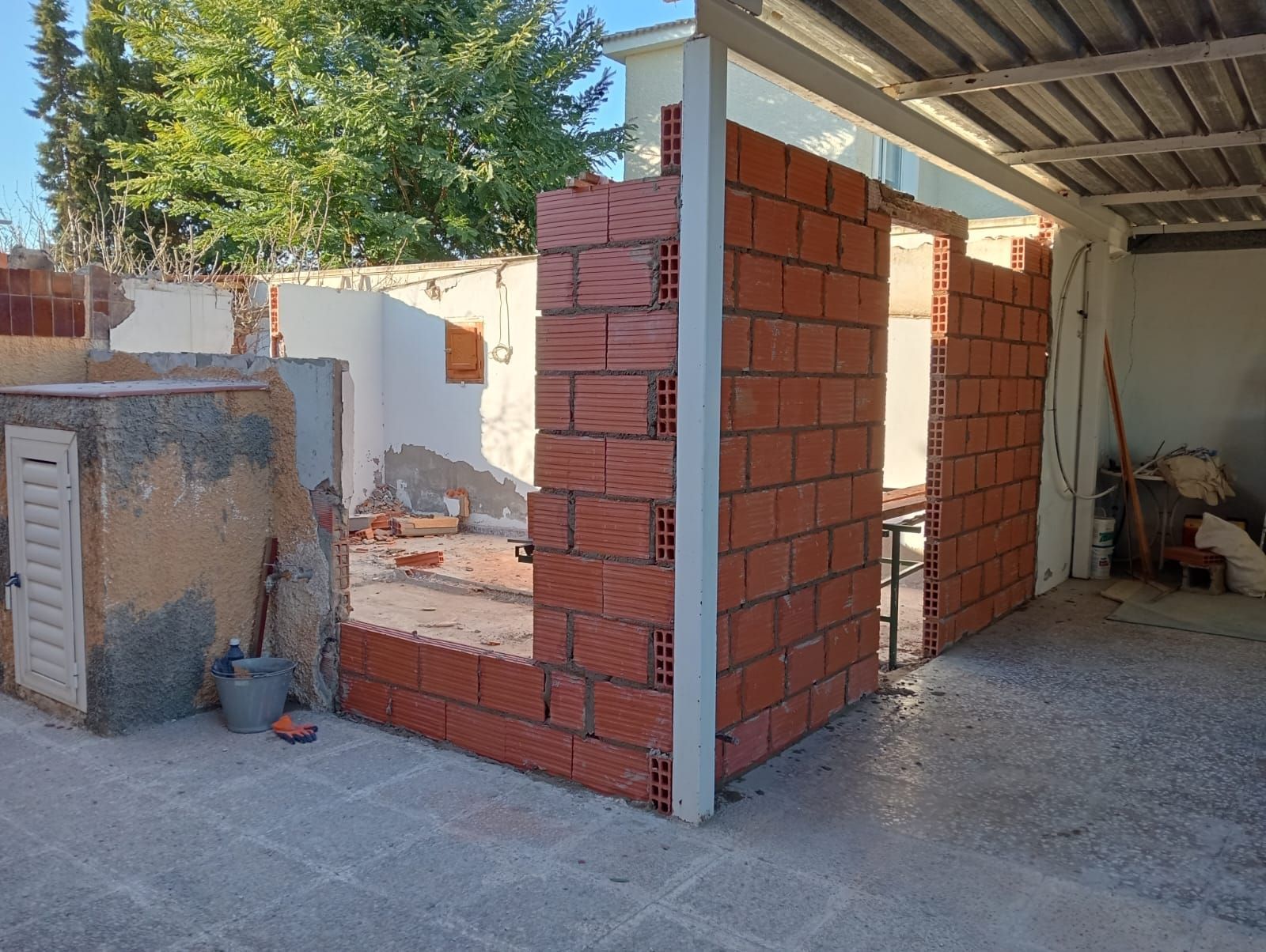 Se está construyendo un muro de ladrillos en el patio trasero de una casa.