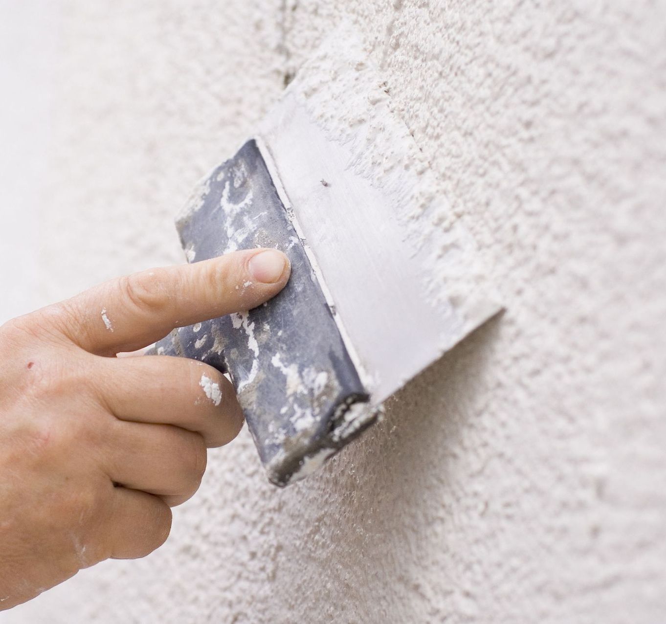 Una persona está enyesando una pared con una espátula.