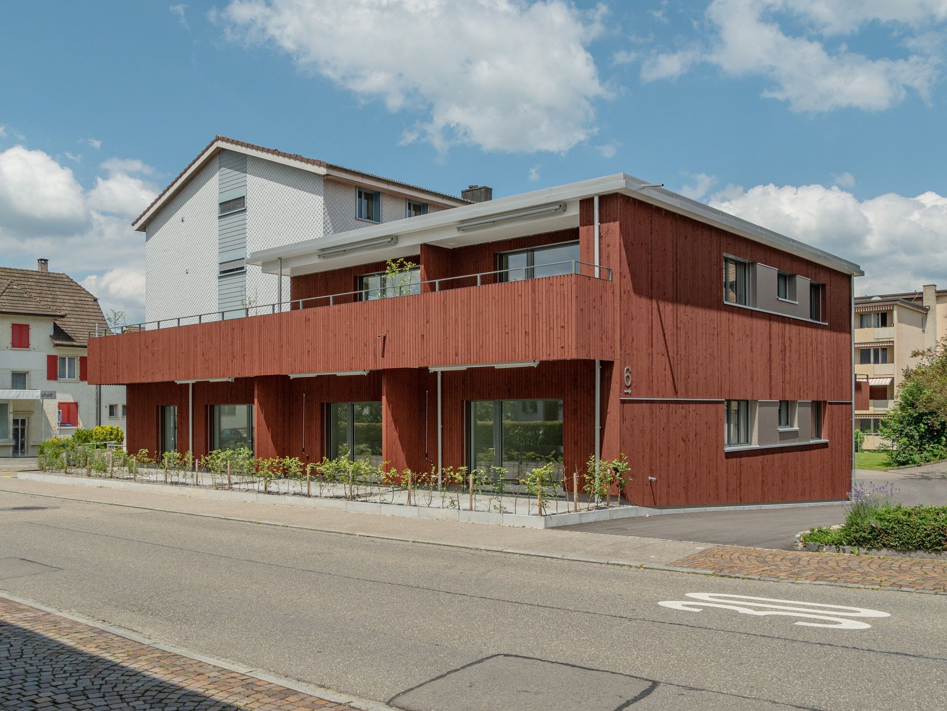 Modernes, rot-weisses zweistöckiges Gebäude in einer ruhigen Strasse unter blauem Himmel