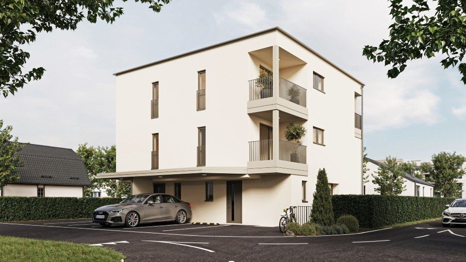 Modernes weisses Mehrfamilienhaus mit Balkonen, Carport, Parkplatz und angelegter Zufahrt.