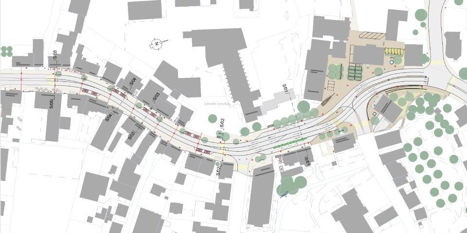 Draufsicht auf eine geschwungene Strasse mit Gebäuden, Gehwegen, Bäumen und Platzflächen