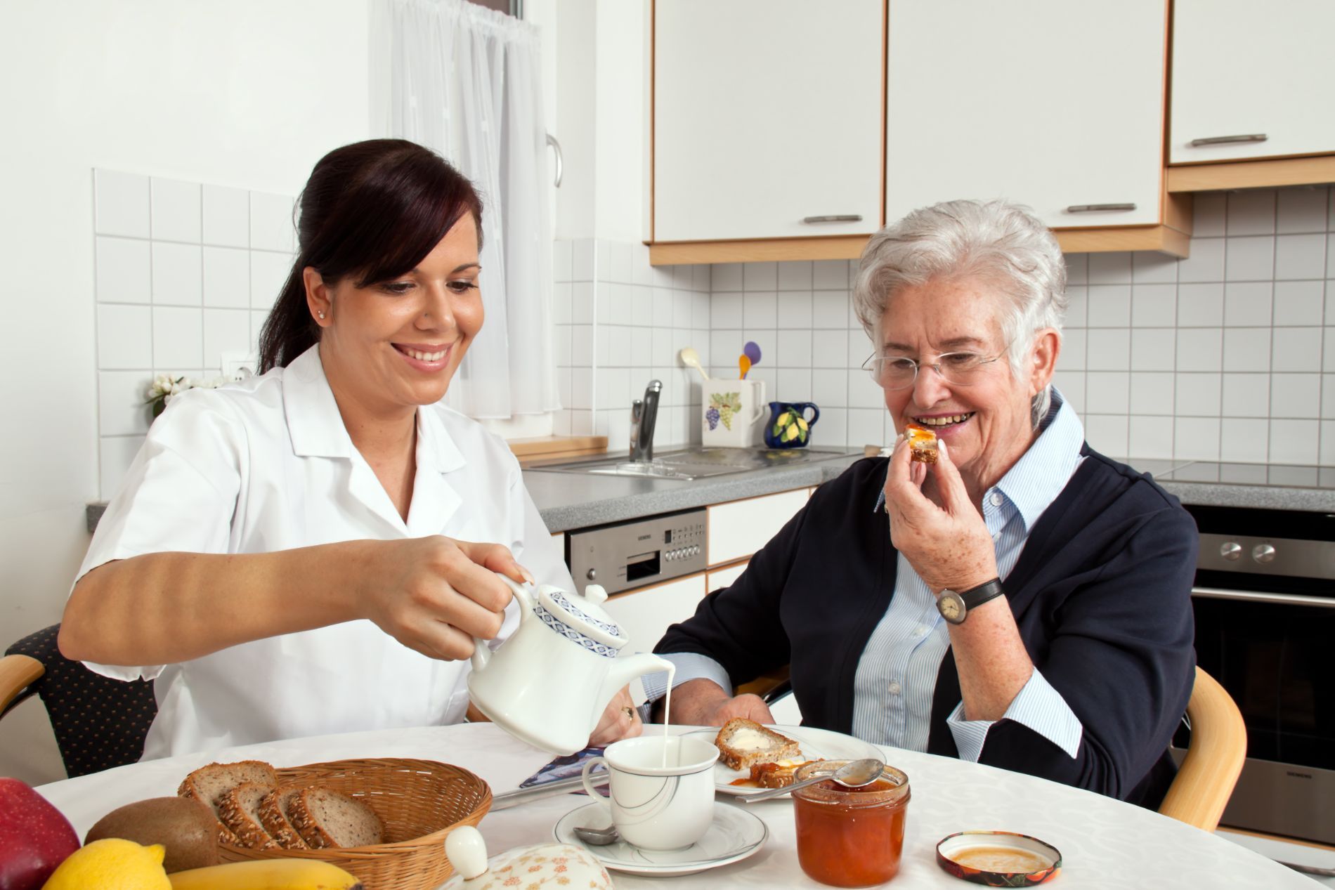 alte Dame und Pflegerin frühstücken gemeinsam