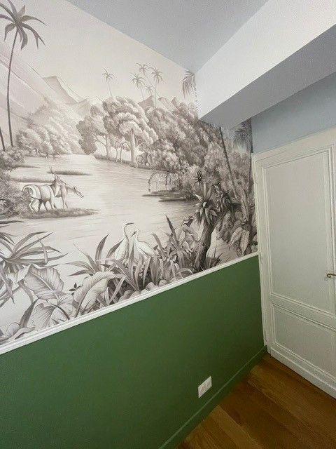 Pièce vide avec parquet clair, murs gris et blancs, mur en briques apparentes.