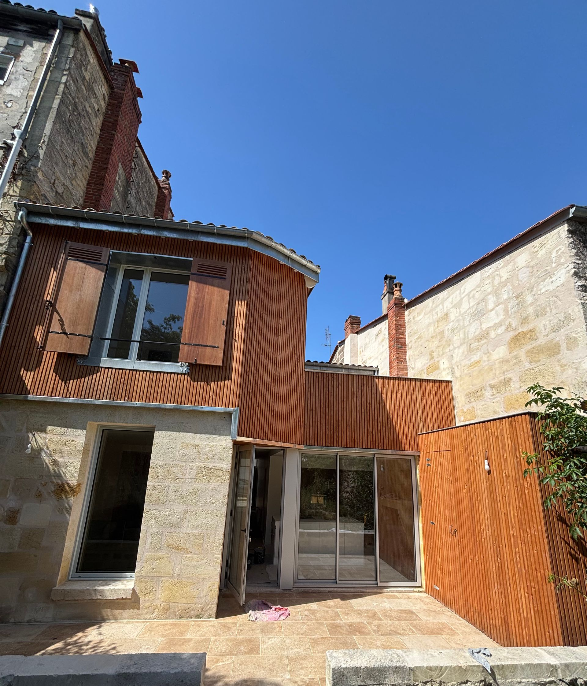 Vue d'angle d'un bâtiment en pierre couleur crème avec une porte bleu foncé, un balcon en fer forgé et un panneau de rue bleu.